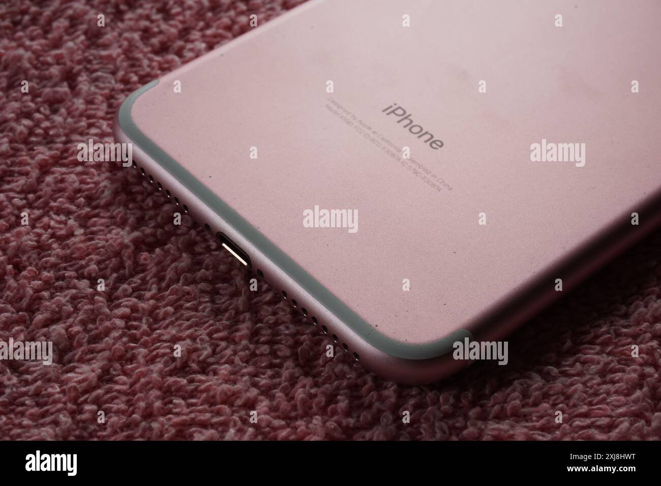 Terengganu, Malaisie - 2 août 2024 : gros plan de pomme rose iphone 7 plus téléphone sur fond rouge. Panneau arrière de l'appareil iphone. Logo iPhone. Banque D'Images