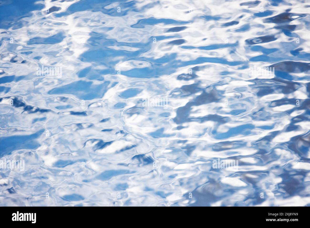 Surface de l'eau avec des reflets ondulés de ciel bleu, texture de photo de fond naturelle abstraite Banque D'Images