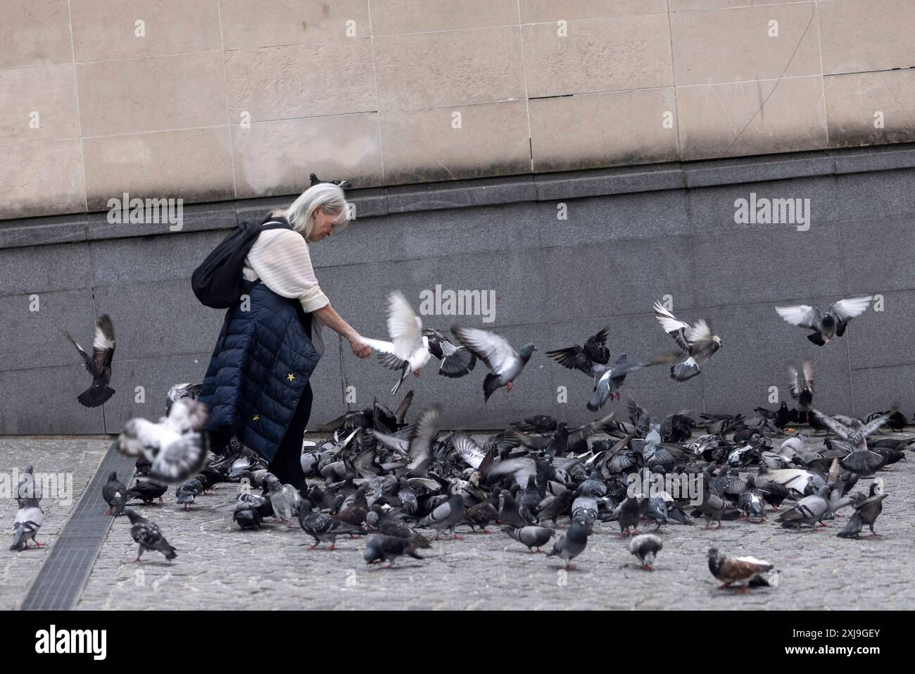 Une femme nourrit les pigeons devant le Centre Pompidou à Paris le 15 juillet 2024 en prévision des Jeux Olympiques de Paris 2024. Pour marquer le lancement des Jeux olympiques de 2024, Nike s'est associé à l'un des monuments les plus célèbres de Paris, le Centre Pompidou, pour une célébration de deux semaines du sport et de la culture. Faisant suite à la récente campagne de la marque montrant la résilience de l'équipe olympique des réfugiés du CIO, l'exposition Art of Victory retracera l'histoire de l'une des innovations les plus décorées de Nike, Air, et son impact sur le monde du sport. Photo Farzaneh Khademian/ABACAPRESS. COM Banque D'Images