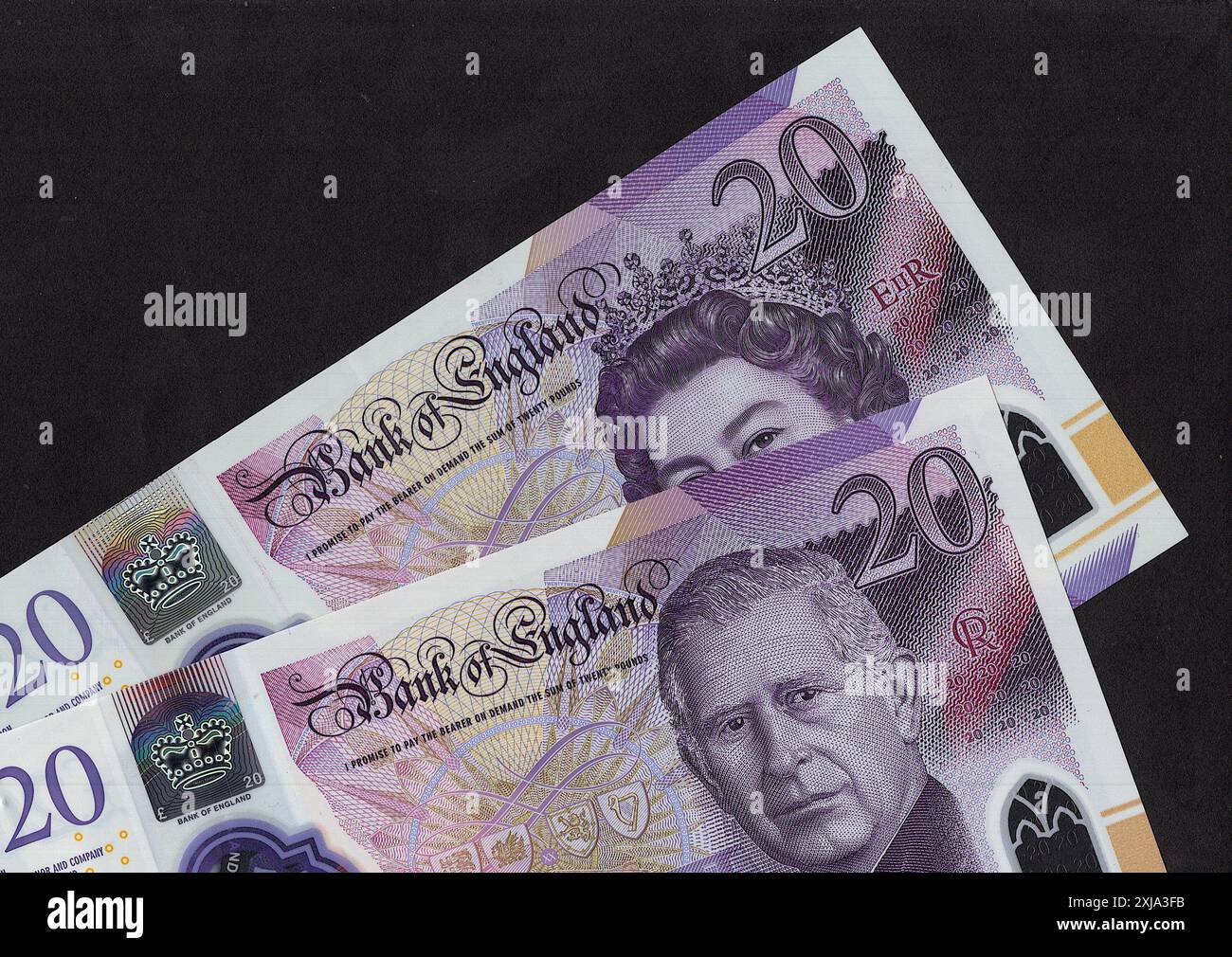 Gros plan de billets de 20 £ du Royaume-Uni avec un portrait du roi Charles III et de la reine Elizabeth II sur fond noir. Banque D'Images