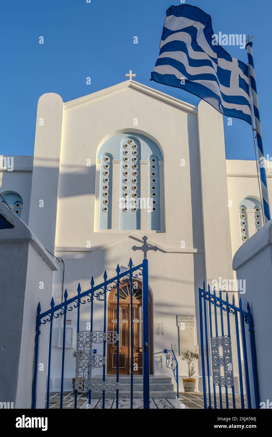 Vue du drapeau grec agitant dans les airs et une église blanchie à la chaux en arrière-plan à iOS Grèce Banque D'Images
