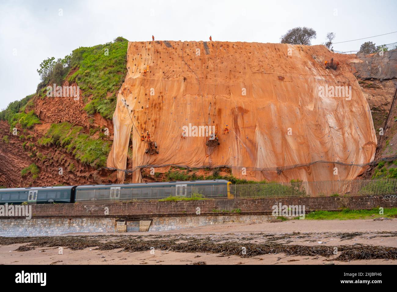 Train sur la ligne de chemin de fer entre Dawlish et Teignmouth Devon, en passant sous les travaux pour stabiliser les falaises de grès Banque D'Images