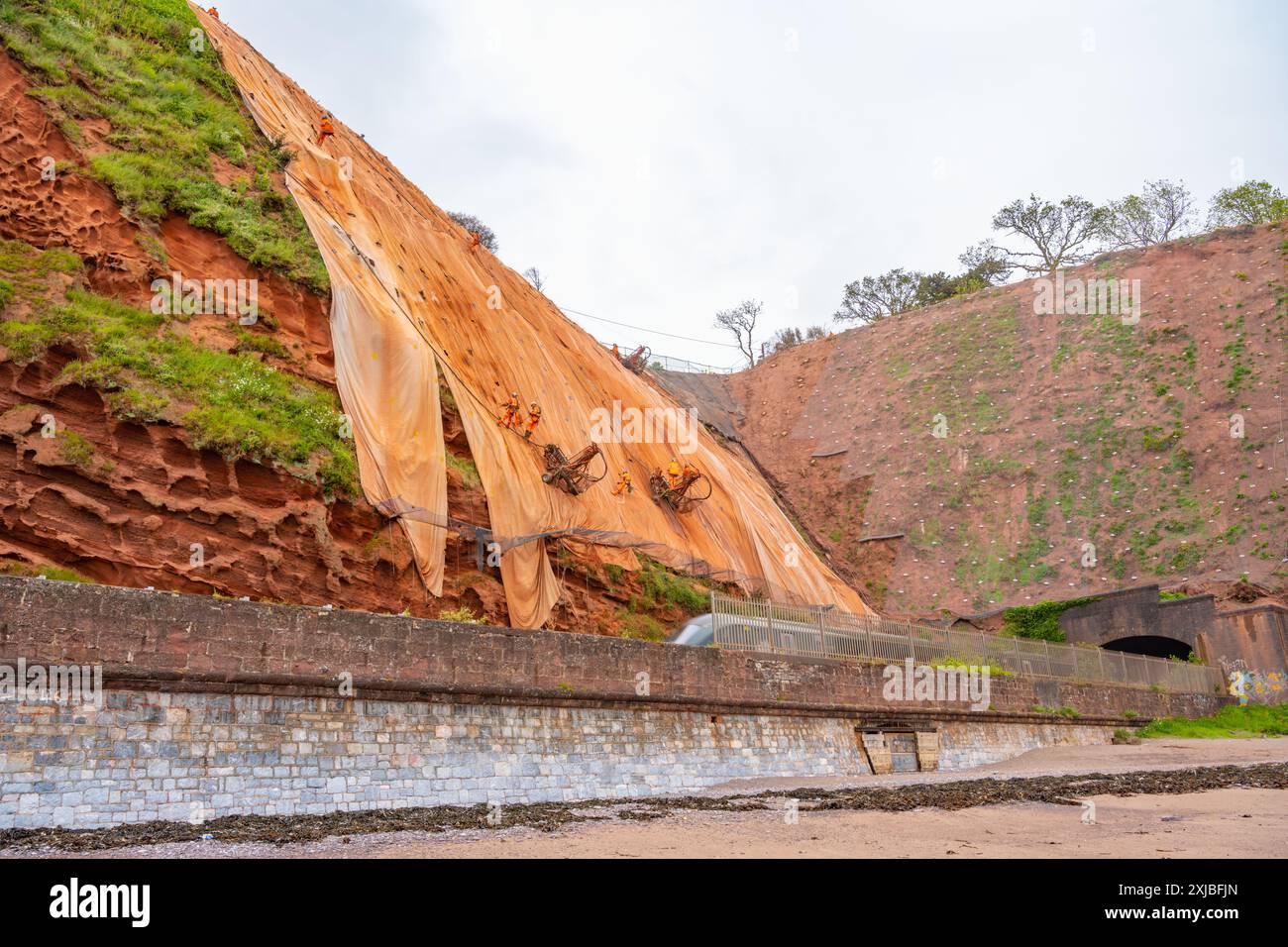 Train sur la ligne de chemin de fer entre Dawlish et Teignmouth Devon, en passant sous les travaux pour stabiliser les falaises de grès Banque D'Images