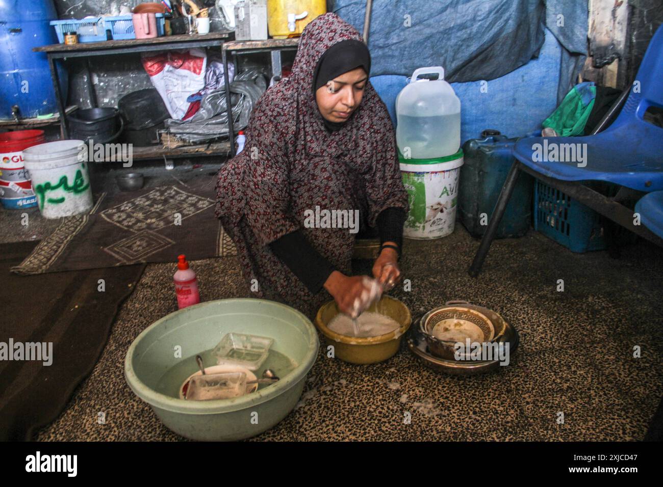 Gaza. 17 juillet 2024. Un membre de la famille d’Ahmed Shinbari lave la vaisselle dans le nord de Gaza, le 17 juillet 2024. Environ 67 pour cent des installations d'approvisionnement en eau, d'assainissement et d'infrastructure ont été détruites ou endommagées dans la bande de Gaza, a déclaré l'Office de secours et de travaux des Nations Unies pour les réfugiés de Palestine dans le proche-Orient (UNRWA) sur la plateforme de médias sociaux X en juin. Crédit : Mahmoud Zaki/Xinhua/Alamy Live News Banque D'Images