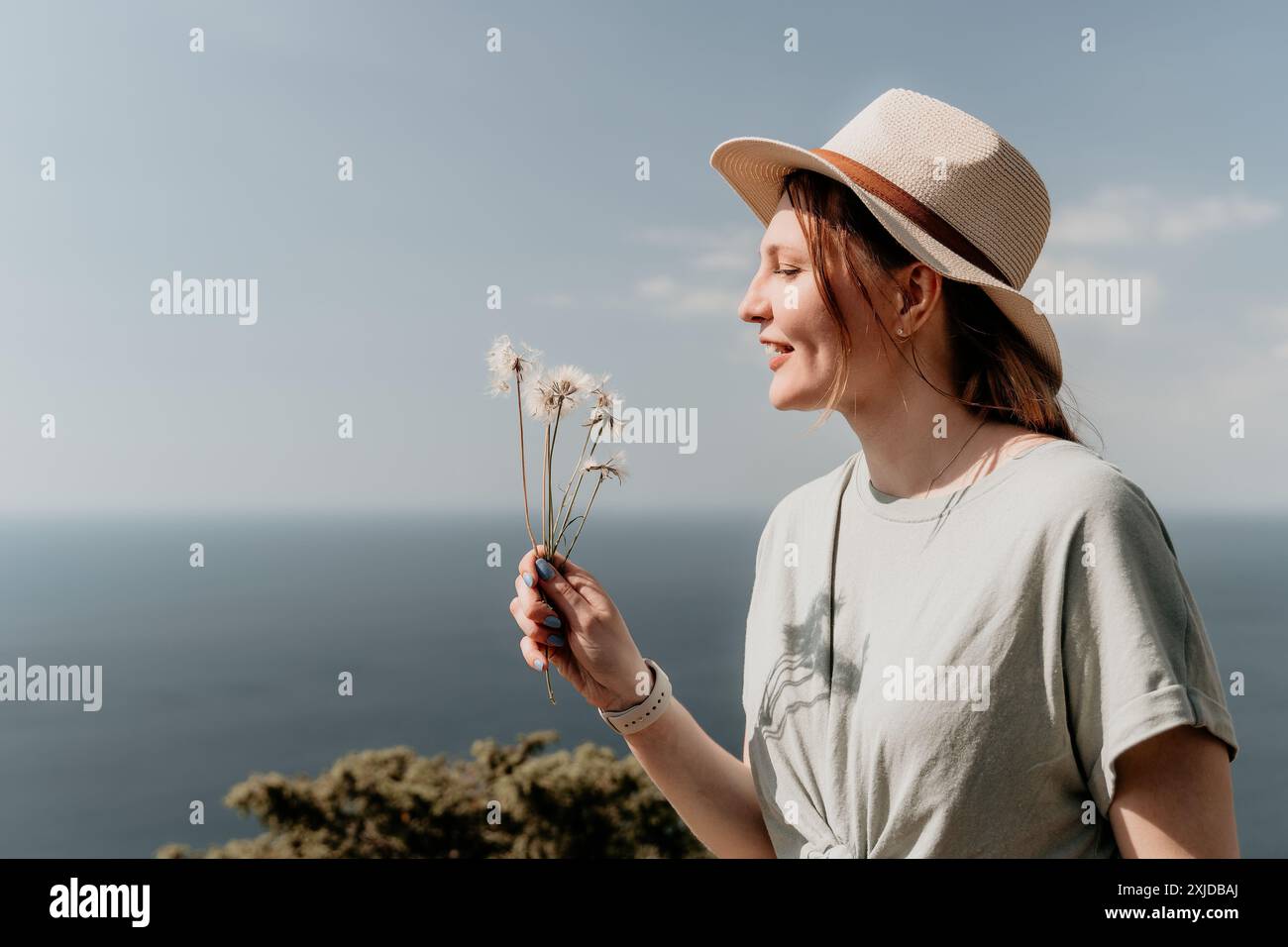 Jeune femme dans un chapeau admirant les pissenlits Banque D'Images