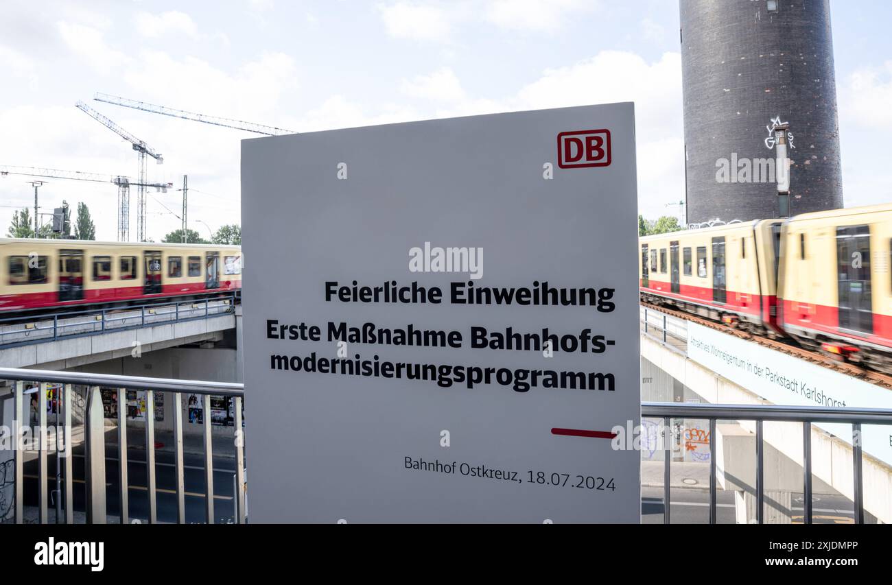 Berlin, Allemagne. 18 juillet 2024. Deux trains S-Bahn passent devant un panneau indiquant « cérémonie d'inauguration - première mesure du programme de modernisation de la gare » à Berlin Ostkreuz. Le projet de construction s'inscrit dans le cadre du programme de modernisation de la gare convenu entre Deutsche Bahn et l'administration des transports de Berlin en 2021. Crédit : Hannes P. Albert/dpa/Alamy Live News Banque D'Images