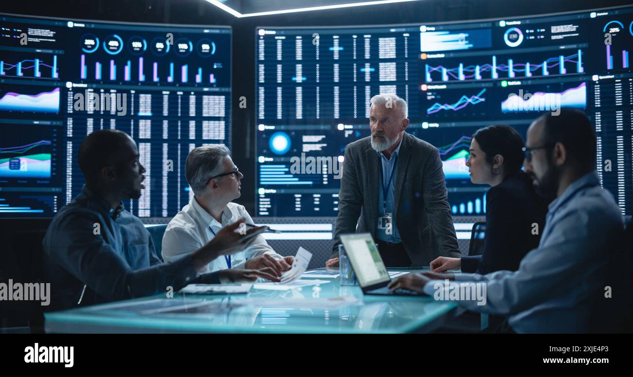 Équipe de scientifiques de données et de développeurs de logiciels discutant des rapports dans la salle de surveillance avec flux analytique sur grand écran numérique. Homme dirigeant la réunion du conseil d'administration de la société d'intelligence artificielle Banque D'Images