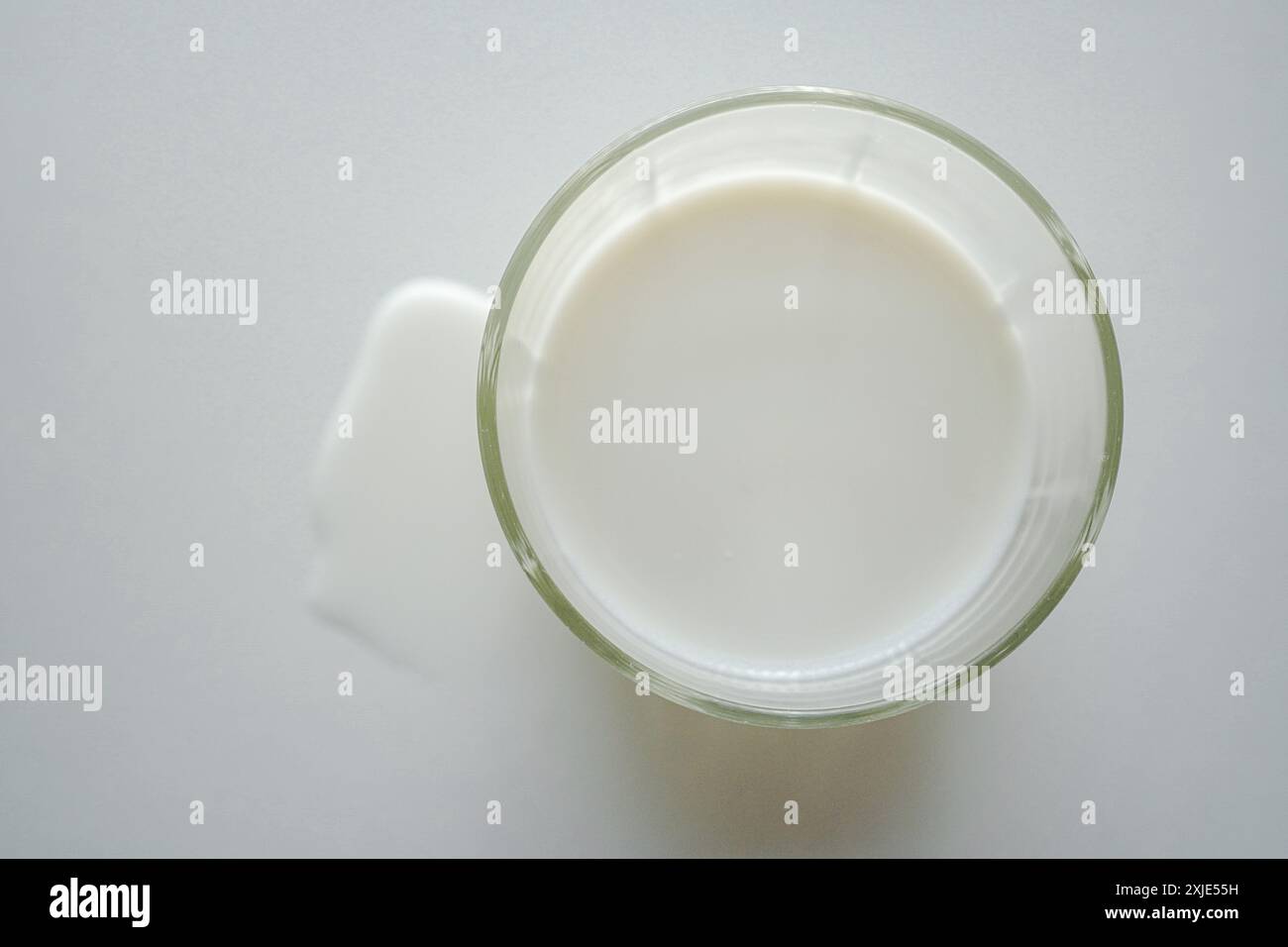 Lait en verre et vue de dessus de lait renversé sur fond blanc Banque D'Images Lait en verre et vue de dessus de lait renversé sur fond blanc Banque D'Images