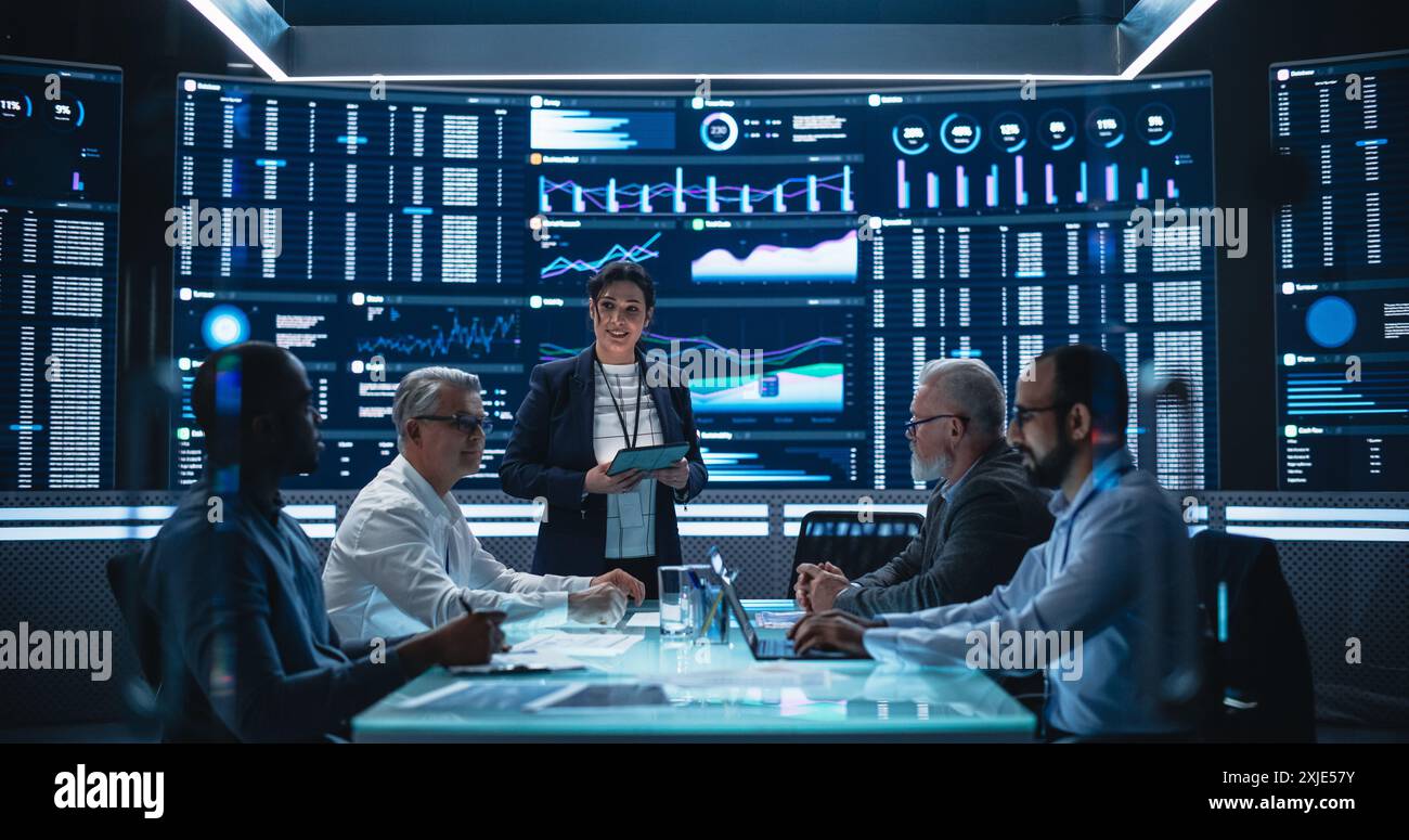 Équipe diversifiée de scientifiques de données et de développeurs de logiciels discutant des rapports dans la salle de surveillance avec flux analytique sur grand écran numérique. Réunion du conseil d'administration de la Femente Artificial Intelligence Company Banque D'Images