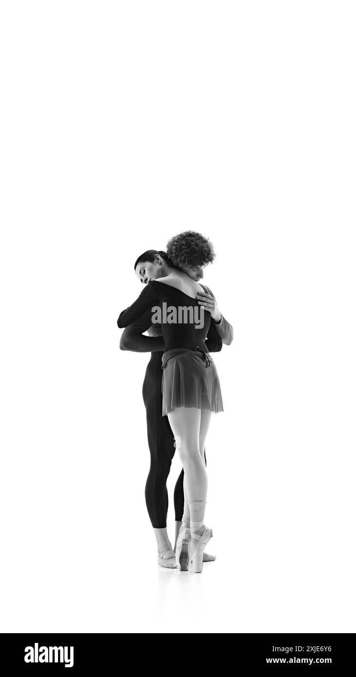 Moment sensible sur la séance d'entraînement quand la ballerine embrasse son partenaire sur fond blanc de studio. Filtre noir et blanc. Banque D'Images