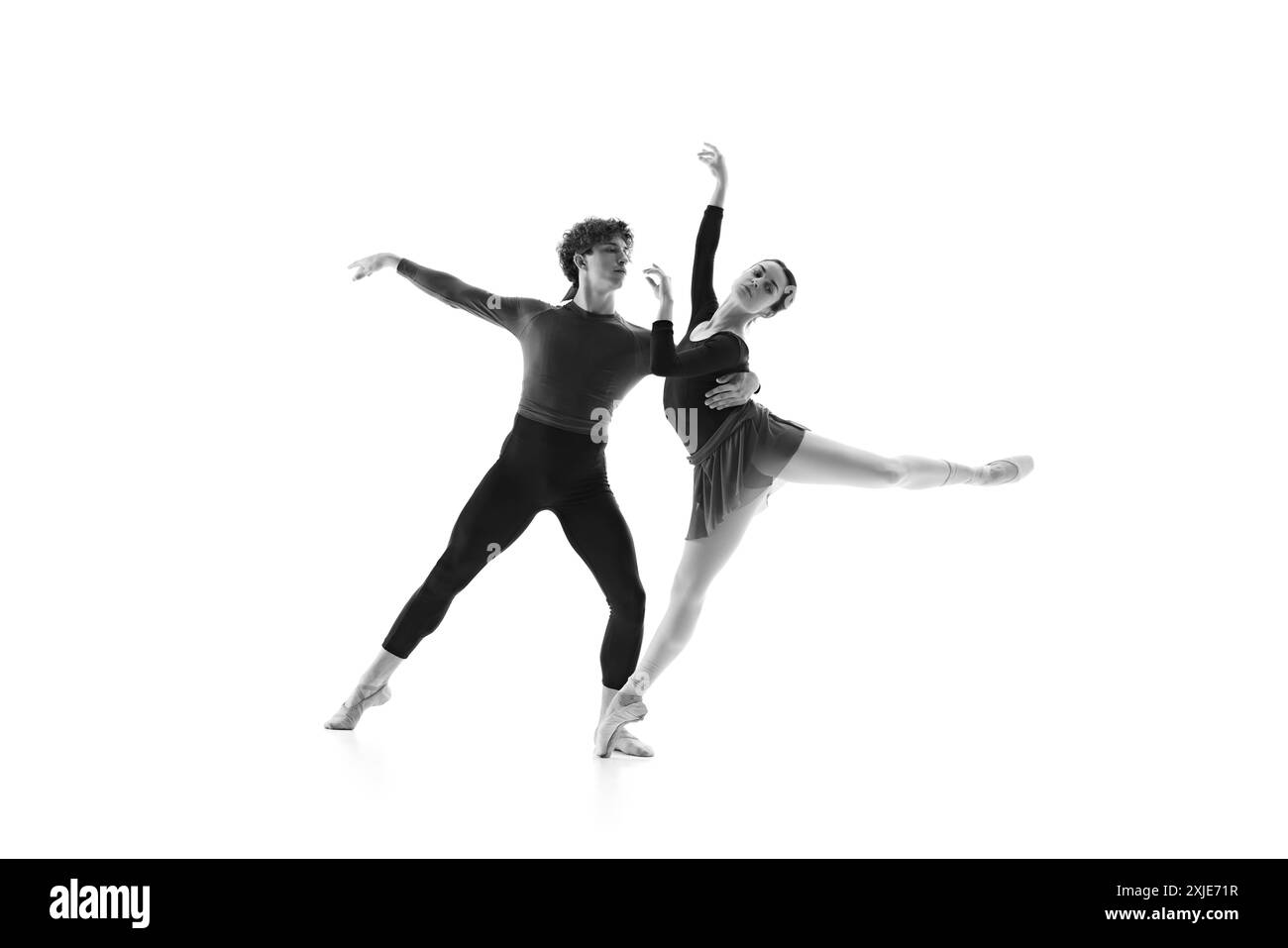Duo de ballet synchronisé lors d'une séance d'entraînement intense sur fond blanc de studio. Filtre monochrome. Élégance. Banque D'Images