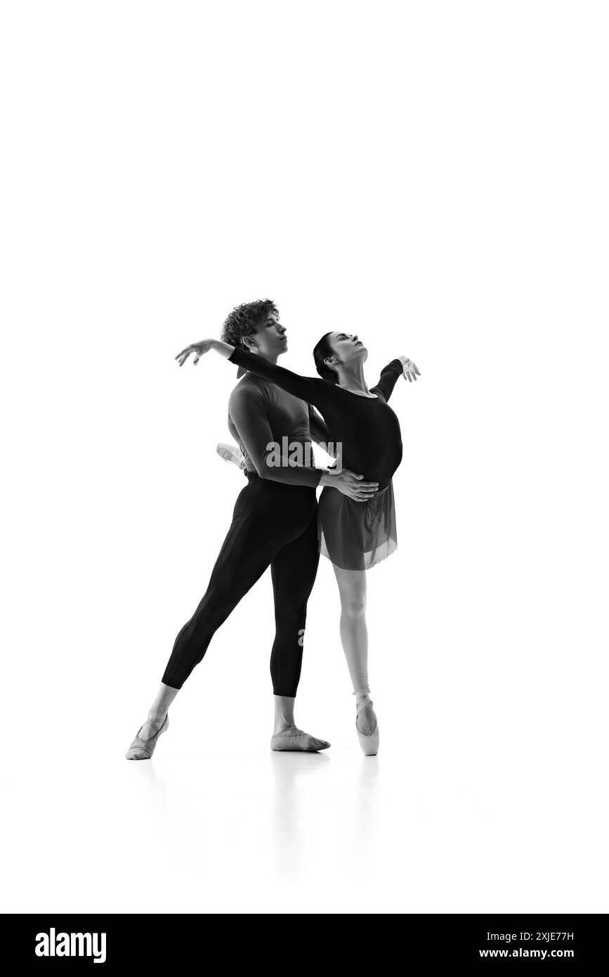 Talentueux jeune homme et femme en formation, synchronisant leurs mouvements pendant la session d'entraînement sur fond blanc de studio. Filtre sépia. Banque D'Images