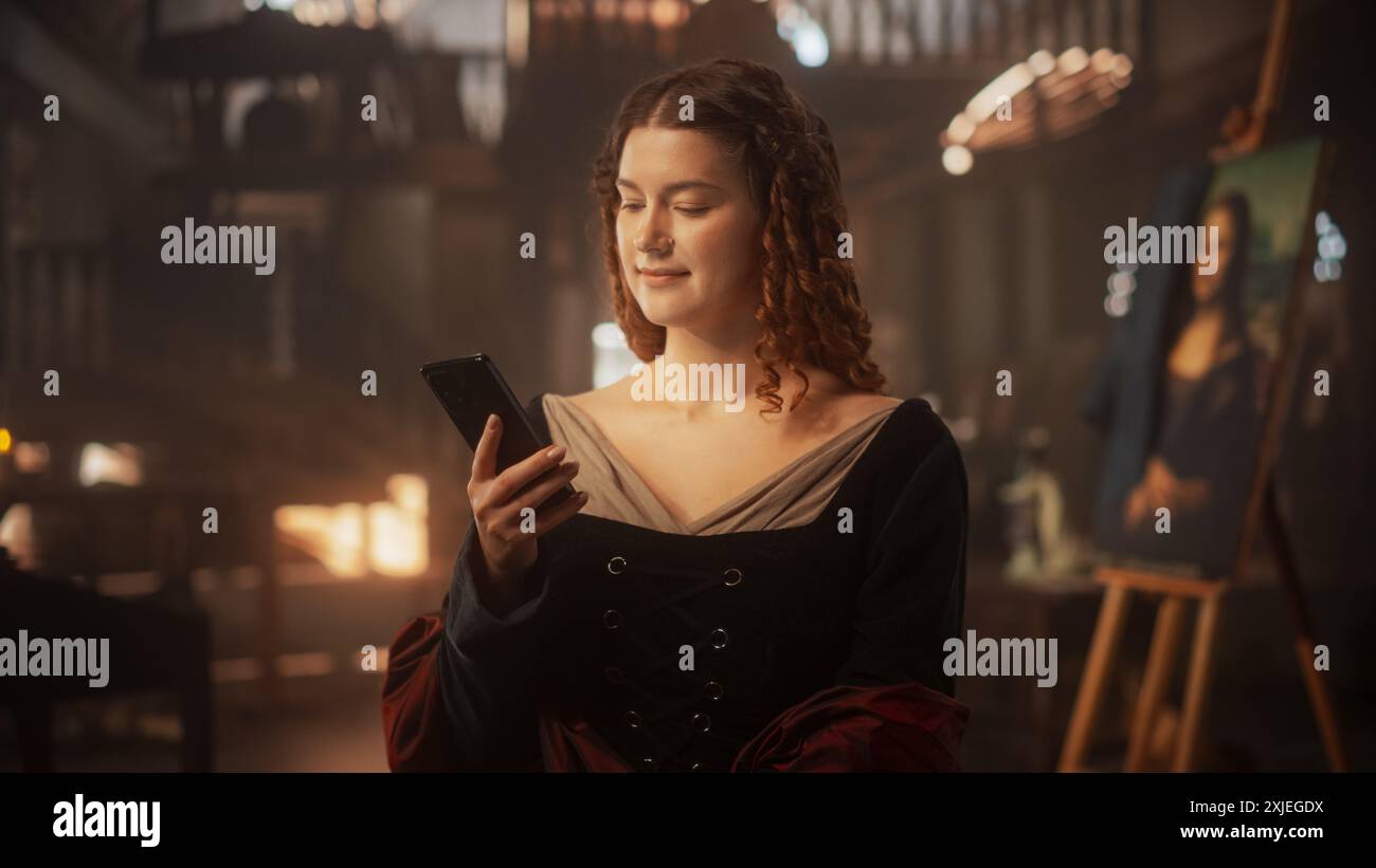 Le passé rencontre le concept actuel : belle jeune femme de l'ère de la Renaissance à l'aide d'un smartphone dans un intérieur antique. Technologie moderne rendant possible le fait de rester connecté pour figure historique Banque D'Images