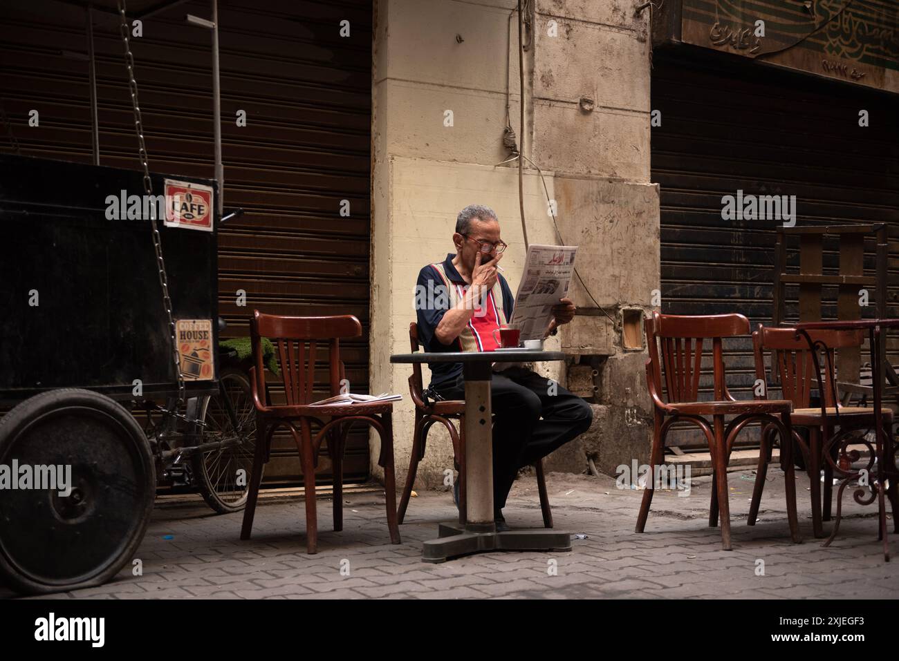Le Caire, Égypte. 14 juin 2024 un égyptien fume, boit du thé et lit un journal dans un café local au centre-ville du Caire, Egypte. Banque D'Images