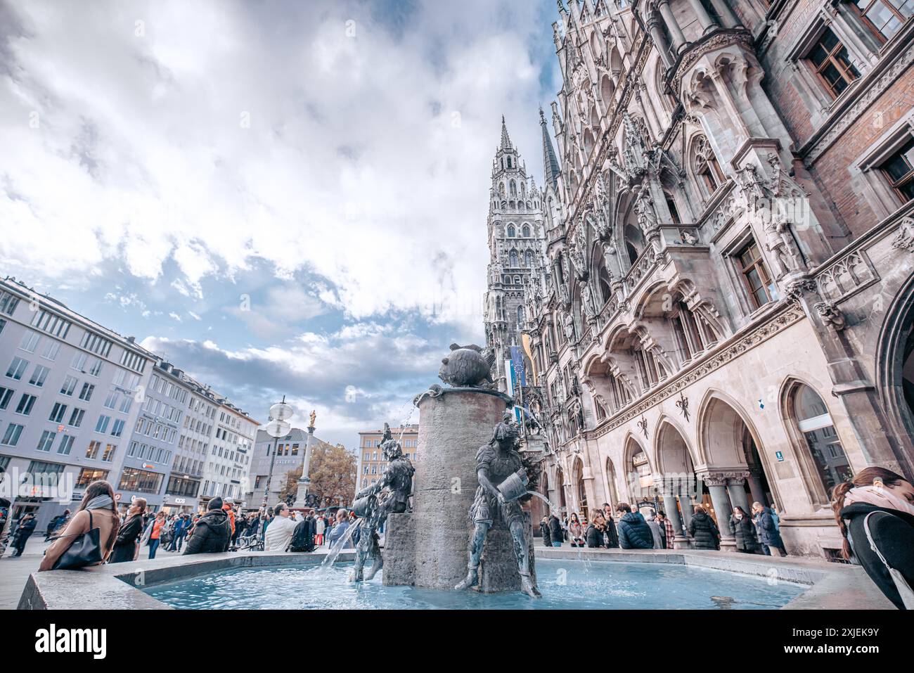 Munich, Allemagne - date inconnue : la Frauenkirche, ou nouvel hôtel de ville de Munich, domine une fontaine et une foule de gens dans la Marienplatz. Banque D'Images