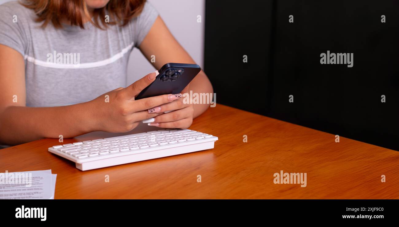 technologie et concepts de communication d'entreprise. une jeune femme d'affaires devant son ordinateur tenant un téléphone intelligent dans ses mains. ma. d'affaires en ligne Banque D'Images