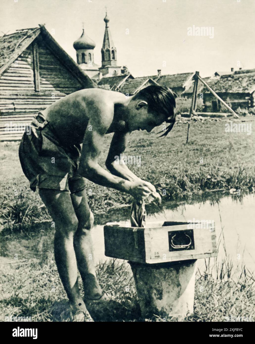 Une photographie montre un soldat allemand nettoyant ses vêtements pendant un moment d'arrêt en territoire soviétique occupé. Prise lors de l'opération Barbarossa en 1941, cette image illustre les tâches routinières et personnelles que les soldats ont accomplies au milieu de l'avancée en cours contre les forces soviétiques sur le front de l'est. Banque D'Images