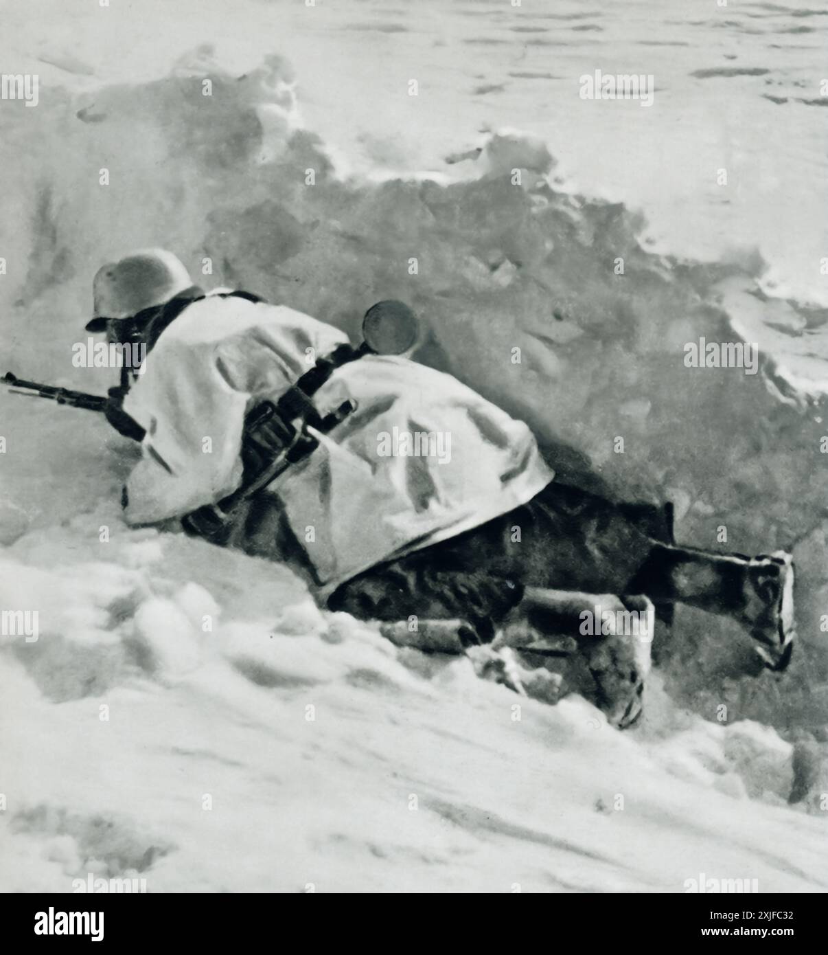 Une photographie montre un soldat allemand rampant près d'un banc de neige, se dirigeant vers la position de tir de première ligne. Prise lors de l'opération Barbarossa en 1941, cette image met en évidence les conditions hivernales extrêmes et les défis auxquels les forces allemandes ont été confrontées lors de leur avancée contre les troupes soviétiques sur le front de l'est pendant la seconde Guerre mondiale. Banque D'Images