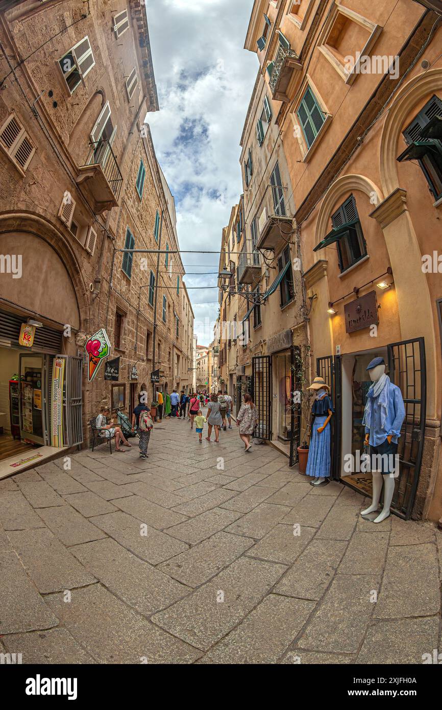 ALGHERO, ITALIE - 3 JUILLET 2024 : rue pittoresque médiévale typique sarde avec petits restaurants traditionnels et boutiques de souvenirs. Banque D'Images