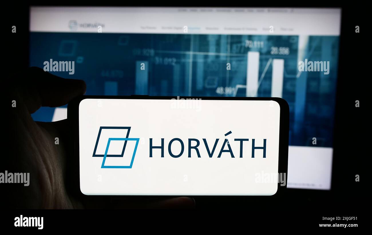 Personne tenant le téléphone portable avec le logo de la société allemande de conseil en gestion Horvath AG en face de la page Web de l'entreprise. Concentrez-vous sur l'affichage du téléphone. Banque D'Images