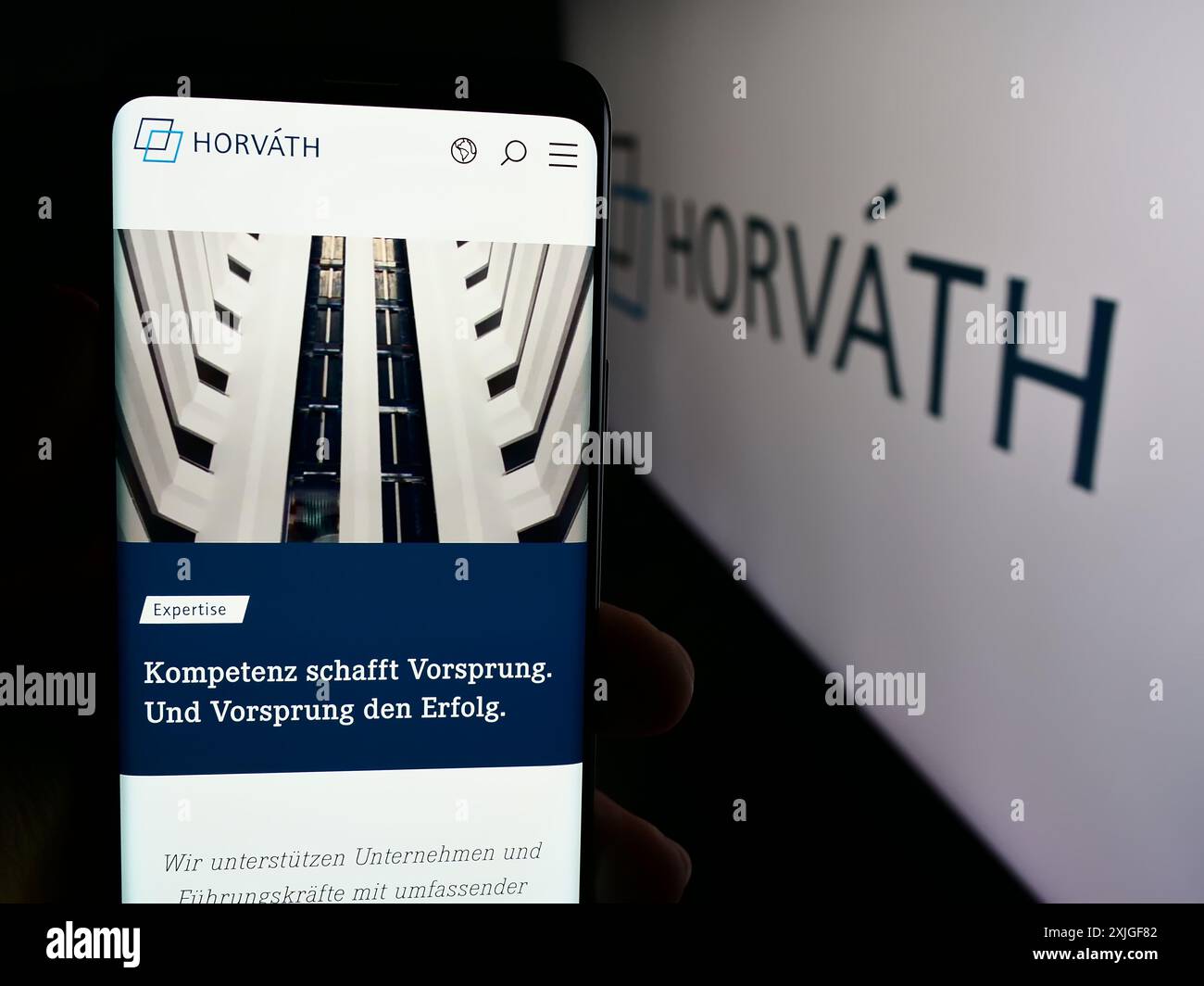 Personne tenant le téléphone portable avec la page Web de la société allemande de conseil en gestion Horvath AG devant le logo. Concentrez-vous sur le centre de l'écran du téléphone. Banque D'Images