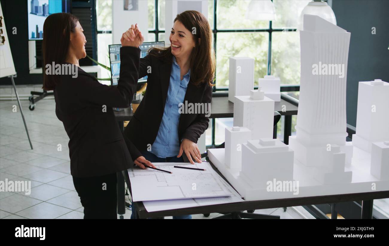 Le personnel de conception donne haut cinq sur la réalisation du succès sur leur tâche de restauration, les travailleurs de l'agence d'architecture coordonnent pour réaliser des plans de fabrication. Des spécialistes de CAO développent des schémas de brouillon. Banque D'Images