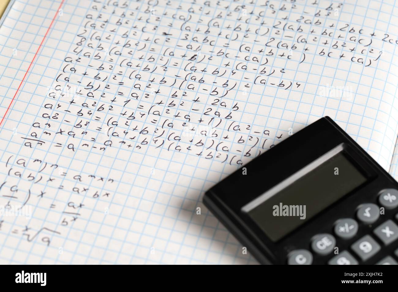 Copybook avec formules mathématiques manuscrites et calculatrice comme arrière-plan, gros plan Banque D'Images