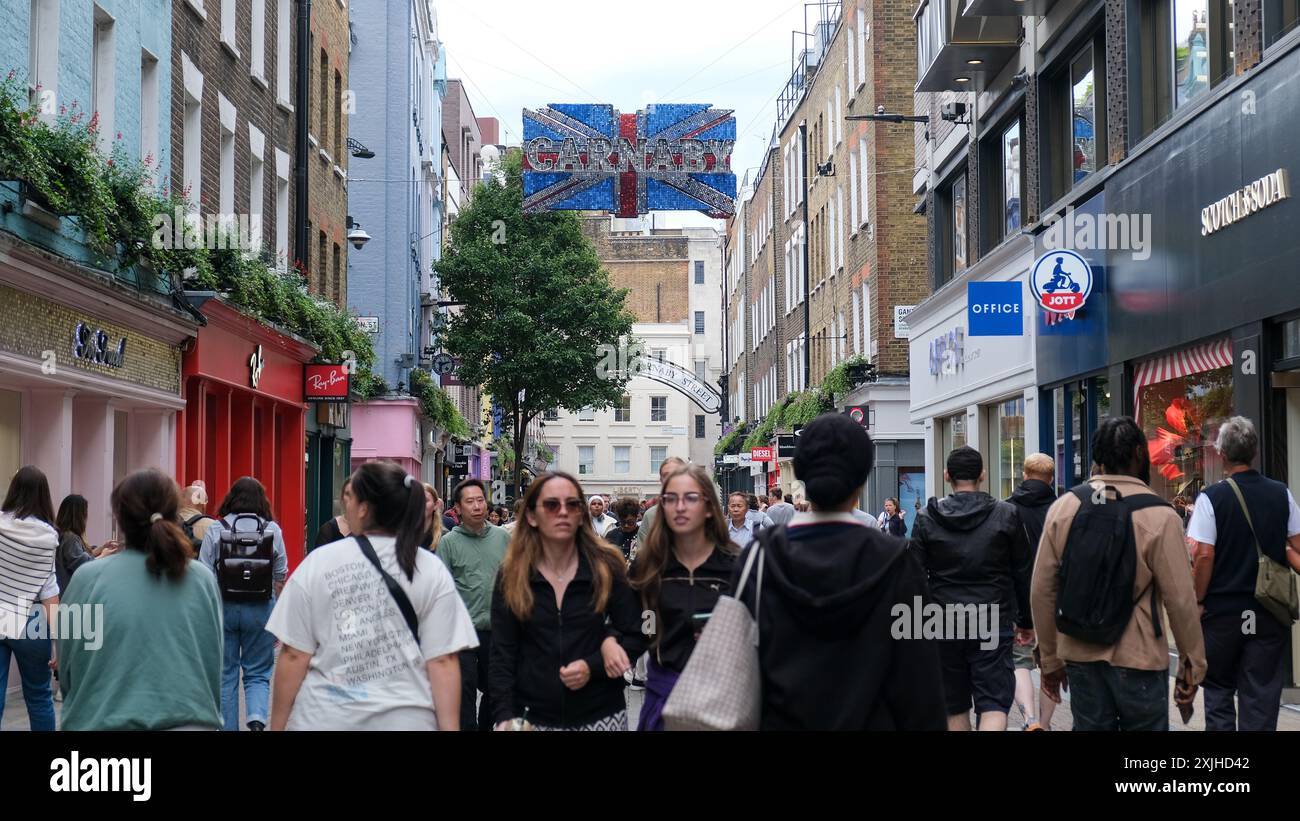 Londres, Royaume-Uni. Les acheteurs de Carnaby Street avec une décoration de drapeau de l'Union suspendue au-dessus de la rue. Banque D'Images