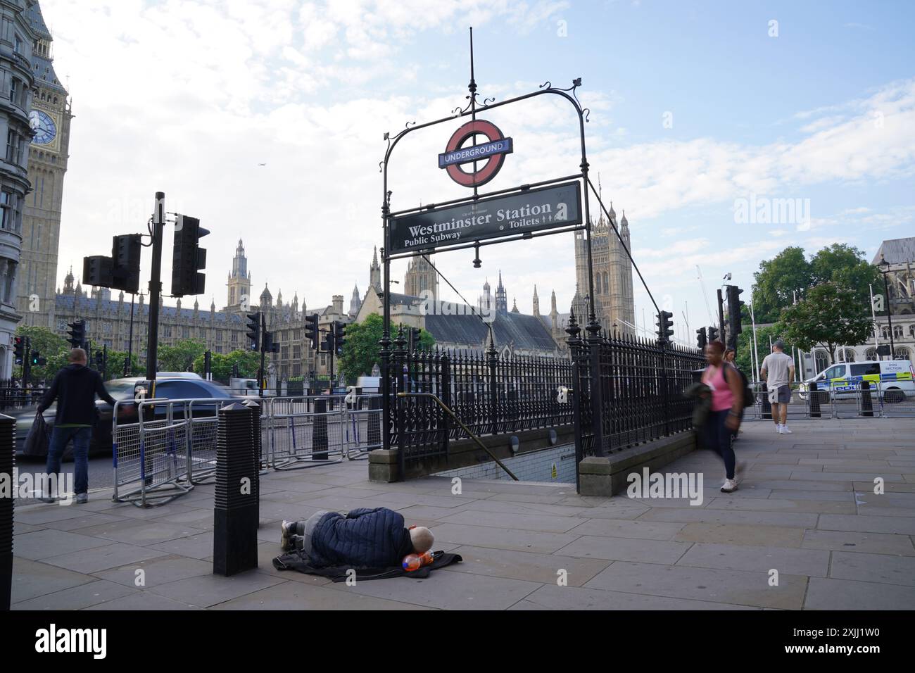 Un sans-abri dormait dans la rue à côté de l'entrée de la station de métro Westminster et dans l'ombre de Big Ben et des chambres du Parlement dans le centre de Londres. Date de la photo : vendredi 19 juillet 2024. Banque D'Images