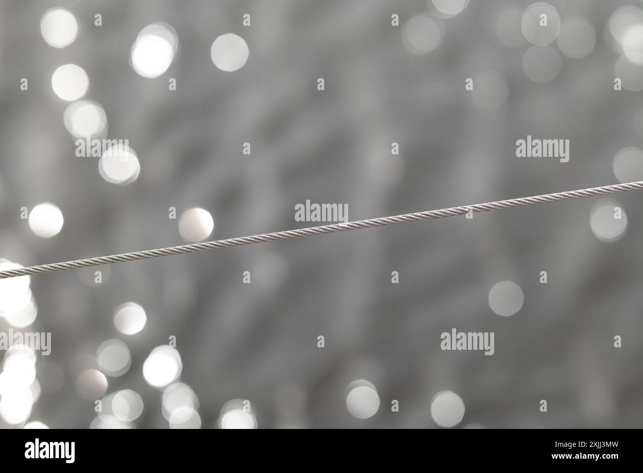 Une corde en acier inoxydable, résistante aux acides avec un tissage sur un fond abstrait avec bokeh. Banque D'Images