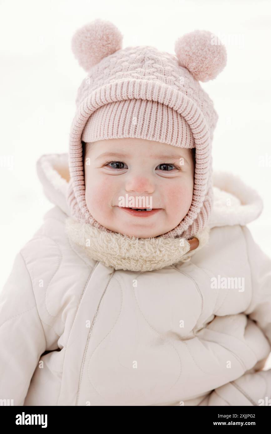 Adorable bébé emballé dans des vêtements d'hiver, souriant dans la neige Banque D'Images