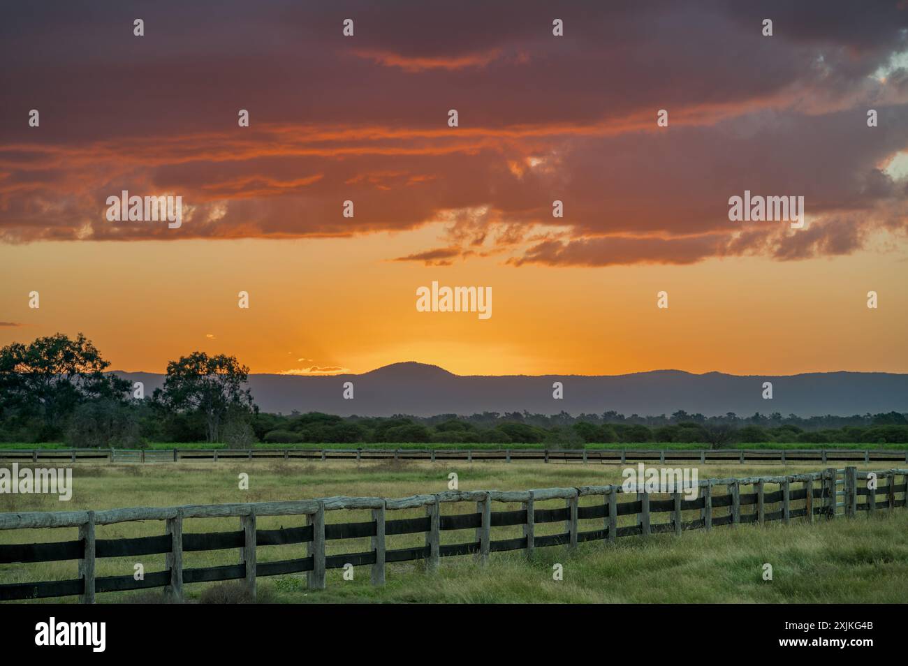 Un paysage de zone humide tranquille et serein avec une vieille clôture de bétail en bois, sur un coucher de soleil d'automne spectaculaire dans le centre du Queensland, en Australie. Banque D'Images