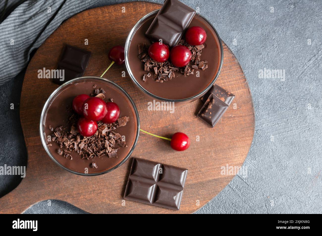Pudding au chocolat et au cacao avec cerise aigre, mousse dans une tasse en verre sur une table rustique, supangle Banque D'Images
