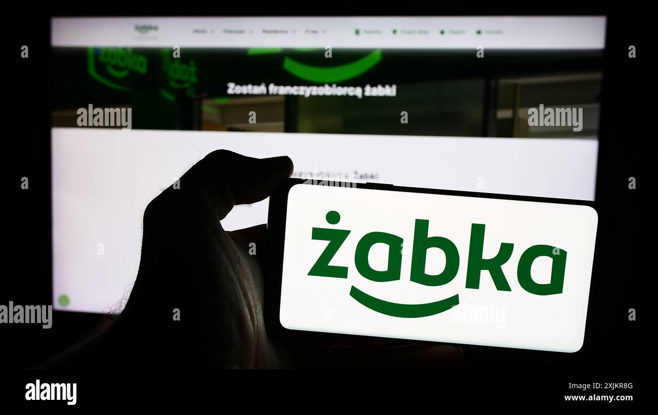 Personne tenant un smartphone avec le logo de la société de détail polonaise Zabka Polska sp. z o.o. devant le site web. Concentrez-vous sur l'affichage du téléphone. Banque D'Images