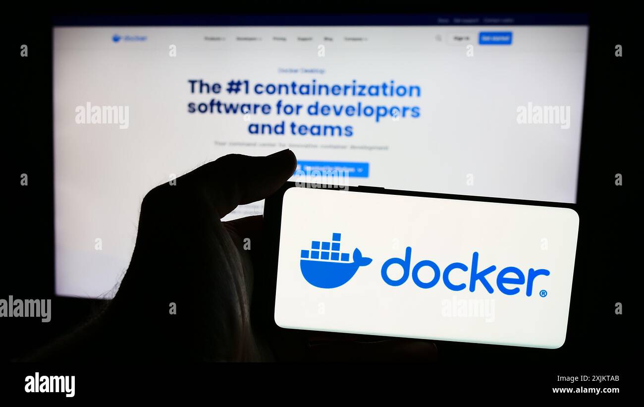 Personne tenant le téléphone portable avec le logo de la société américaine de logiciels de productivité Docker Inc en face de la page Web de l'entreprise. Concentrez-vous sur l'affichage du téléphone. Banque D'Images