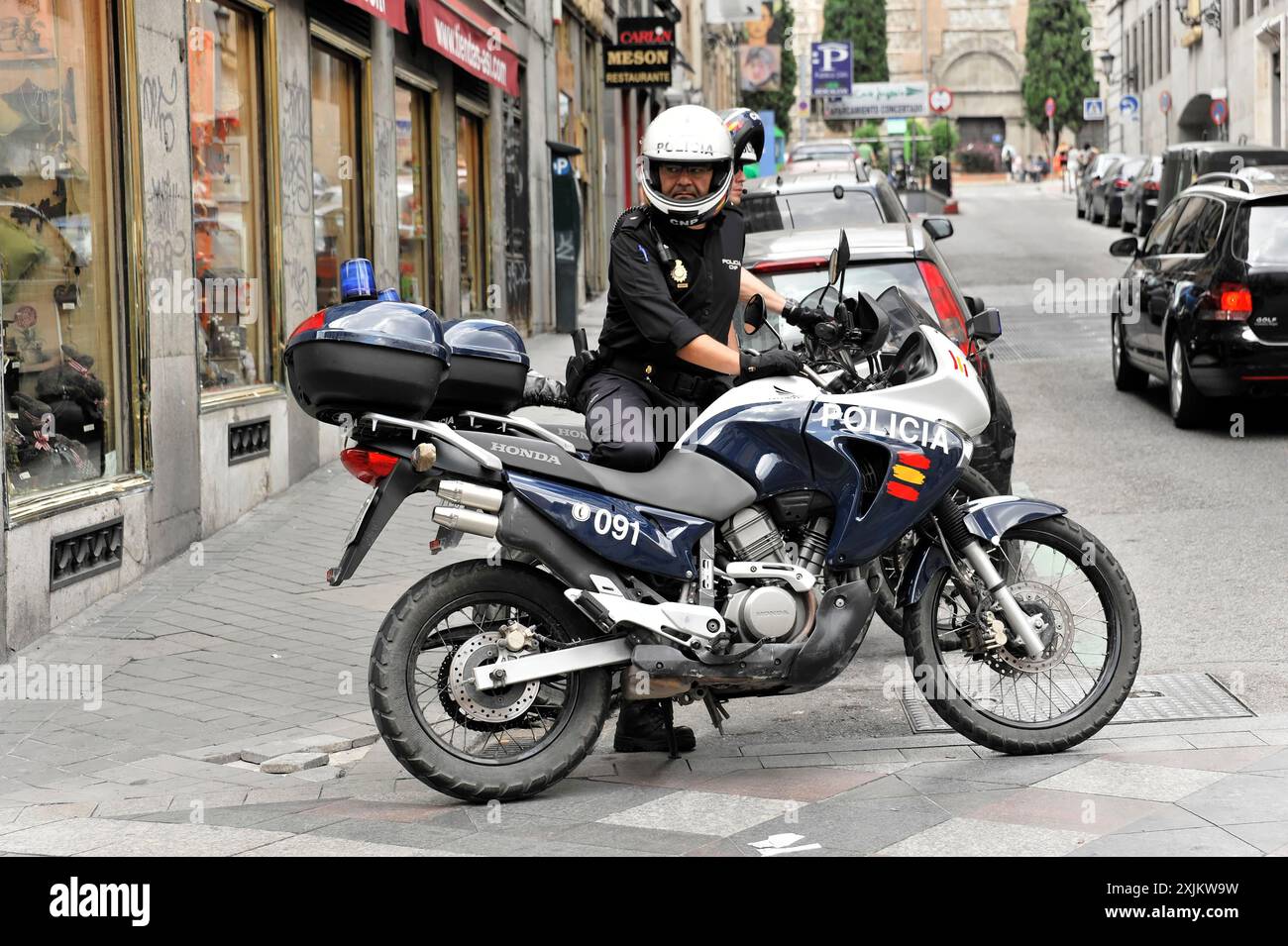 Madrid, Espagne, Europe, Un policier sur une moto s'arrête devant un magasin dans une rue animée de la ville Banque D'Images