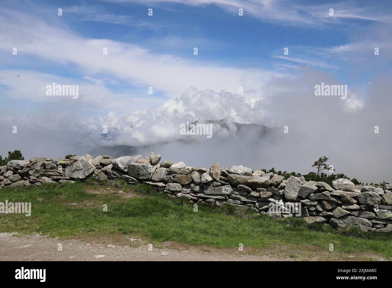 Vue d'un mur de roche, derrière lequel le brouillard du matin et les nuages blancs bloquent la vue sur le Zillertal Banque D'Images