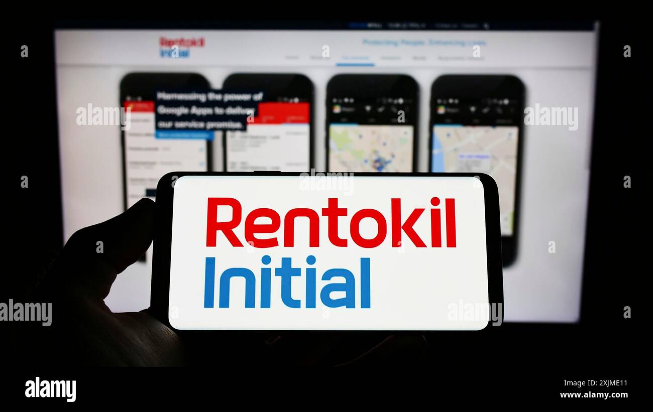 Stuttgart, Allemagne, 06-06-2022 : personne tenant un téléphone portable avec le logo de la société de services britannique Rentokil initial plc sur l'écran en face de la page web. Banque D'Images