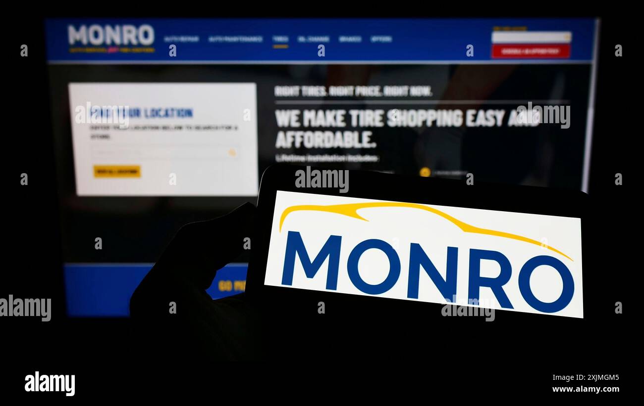 Stuttgart, Allemagne, 07-15-2022 : personne tenant un téléphone portable avec le logo de la société de service automobile américaine Monro Inc. sur l'écran devant l'entreprise Banque D'Images