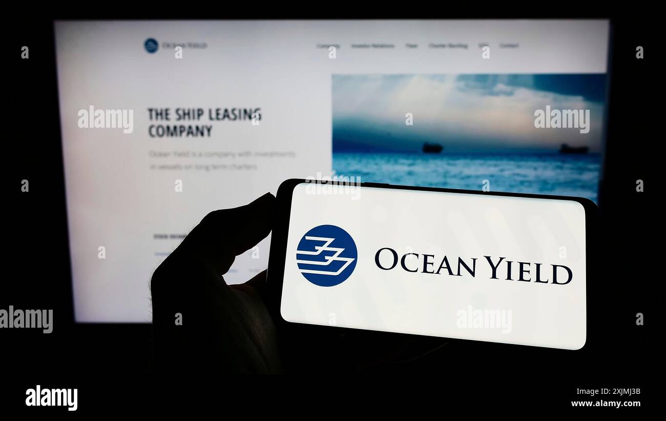 Stuttgart, Allemagne, 07-24-2022 : personne tenant un téléphone portable avec le logo de la société norvégienne de location de navires Ocean Yield COMME sur l'écran en face de la page Web. Banque D'Images