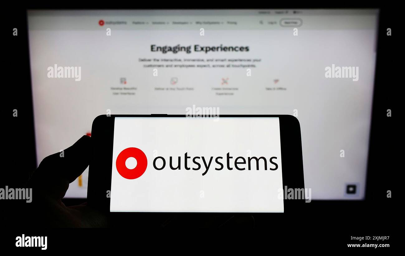 Stuttgart, Allemagne, 07-31-2022, personne tenant un téléphone portable avec le logo de la société de logiciels low-code OutSystems sur l'écran devant le web d'affaires Banque D'Images