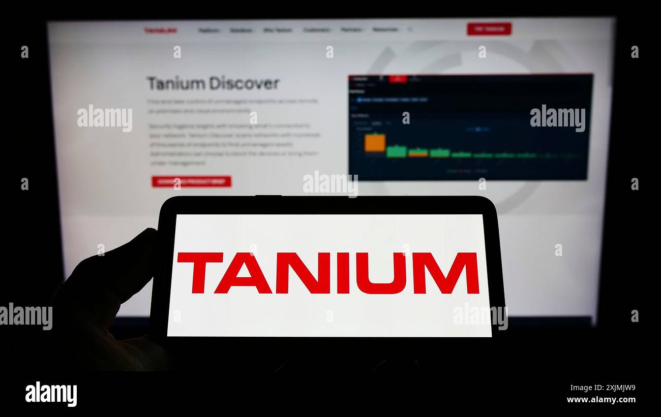 Stuttgart, Allemagne, 07-31-2022, personne tenant un téléphone portable avec le logo de la société américaine de cybersécurité Tanium Inc. sur l'écran devant la page web. Banque D'Images