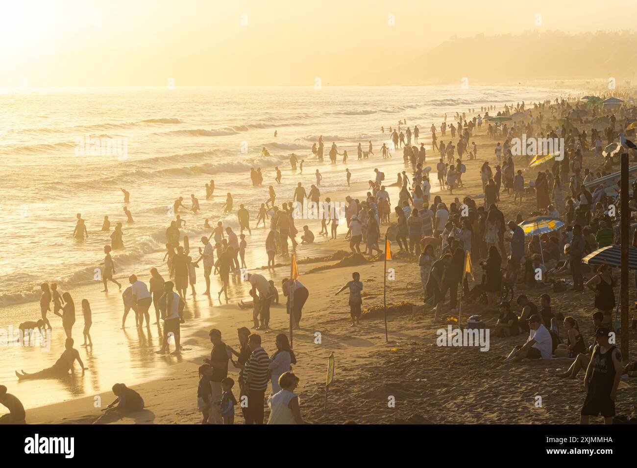 Touristes en silhouette nageant et jouant dans l'océan Pacifique à Santa Monica Beach près de Los Angeles, Californie, à l'heure dorée d'un jour brumeux Banque D'Images