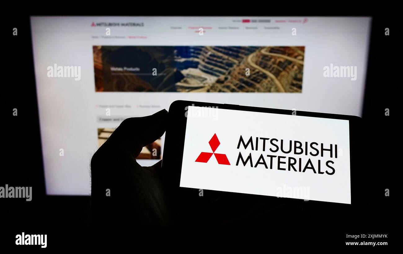 Téléphone portable avec logo de la société Mitsubishi Materials Corporation (MMC) sur l'écran en face de la page Web. Concentrez-vous sur l'affichage du téléphone Banque D'Images