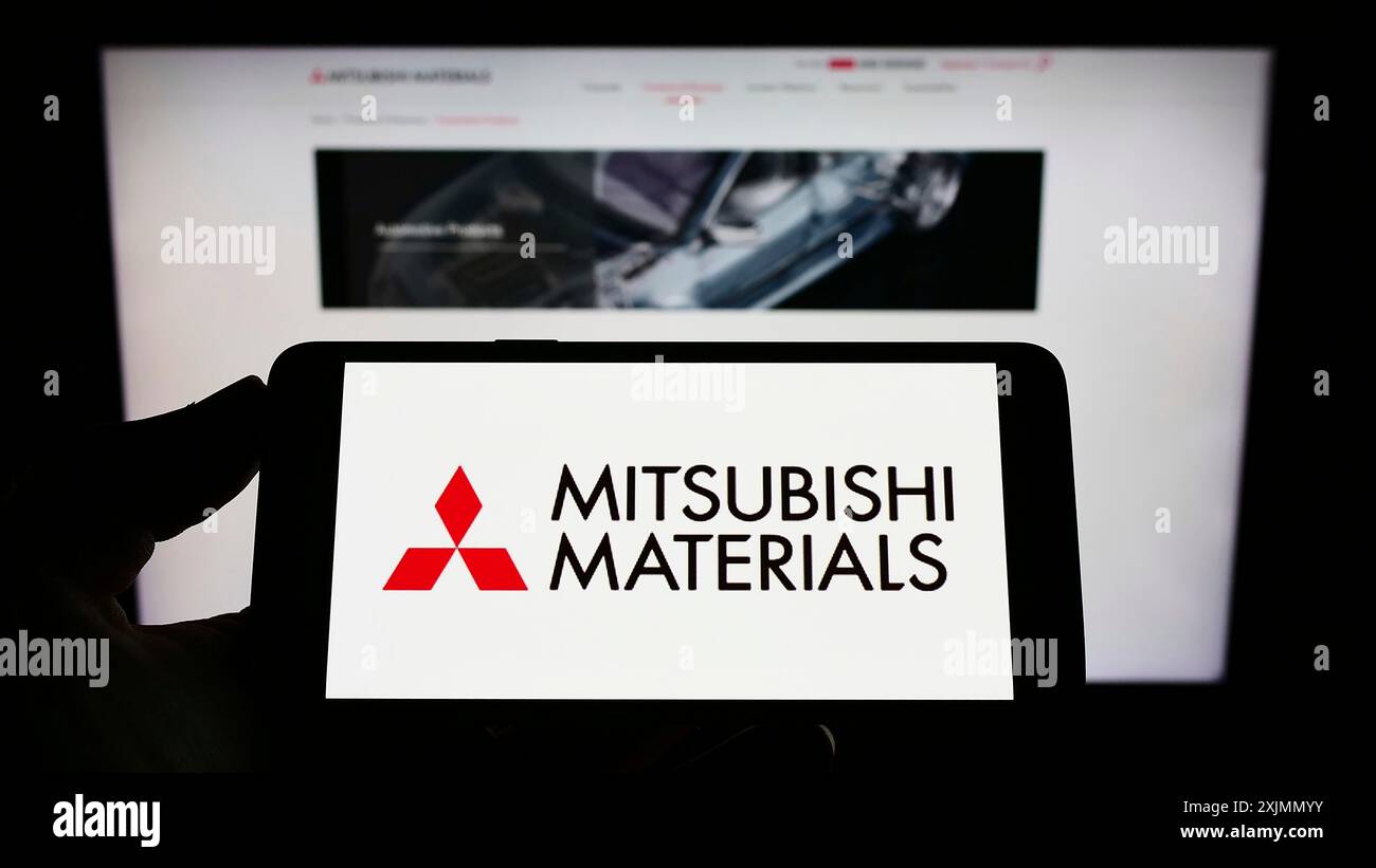 Téléphone portable avec le logo de la société Mitsubishi Materials Corporation (MMC) sur l'écran en face de la page Web. Concentrez-vous sur l'affichage du téléphone Banque D'Images