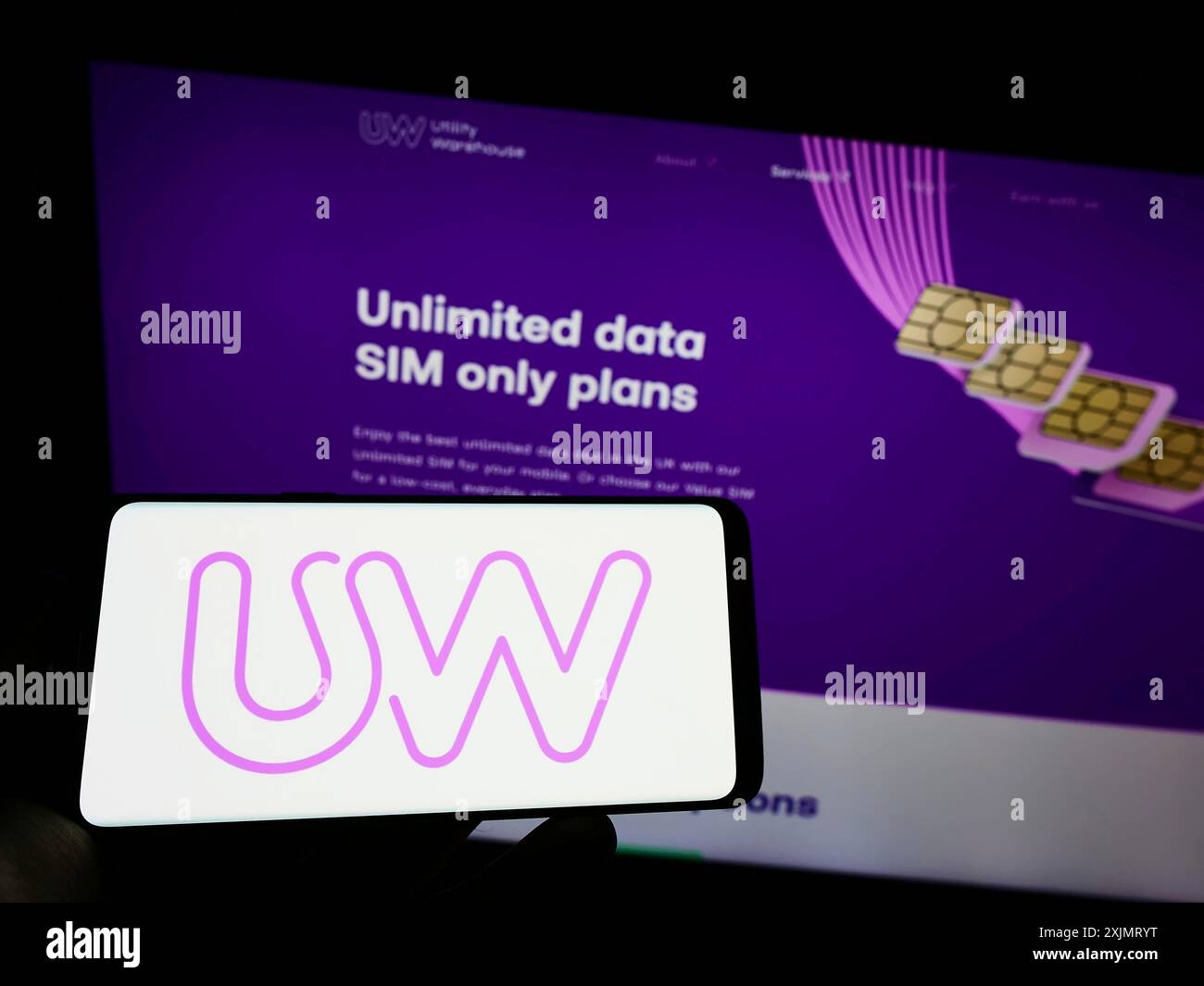 Stuttgart, Allemagne, 10-13-2022 : personne tenant un téléphone portable avec le logo de la société britannique Utility Warehouse (UW) sur l'écran devant la page Web de l'entreprise. Banque D'Images