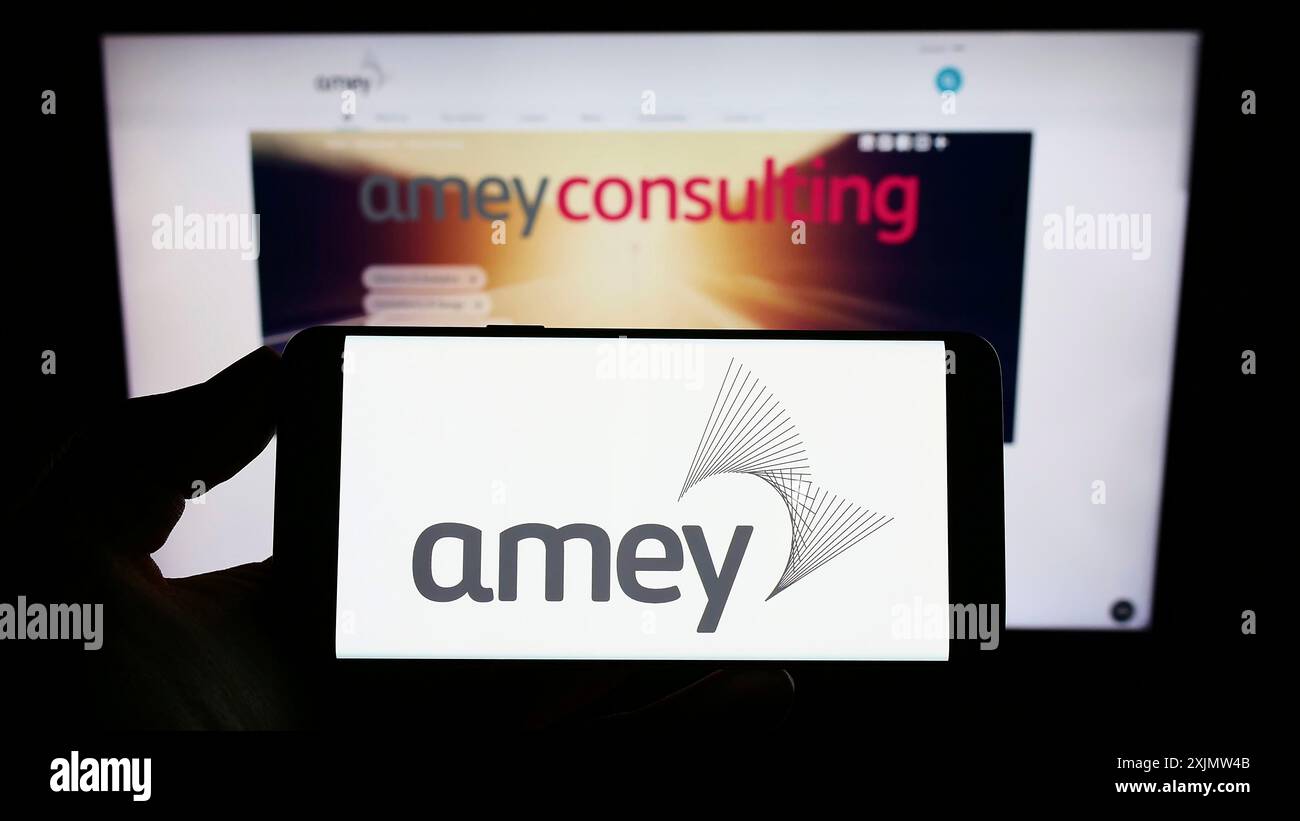 Stuttgart, Allemagne, 10-23-2022 : personne tenant un téléphone portable avec le logo de la société d'infrastructure britannique Amey plc sur l'écran devant le web d'affaires Banque D'Images
