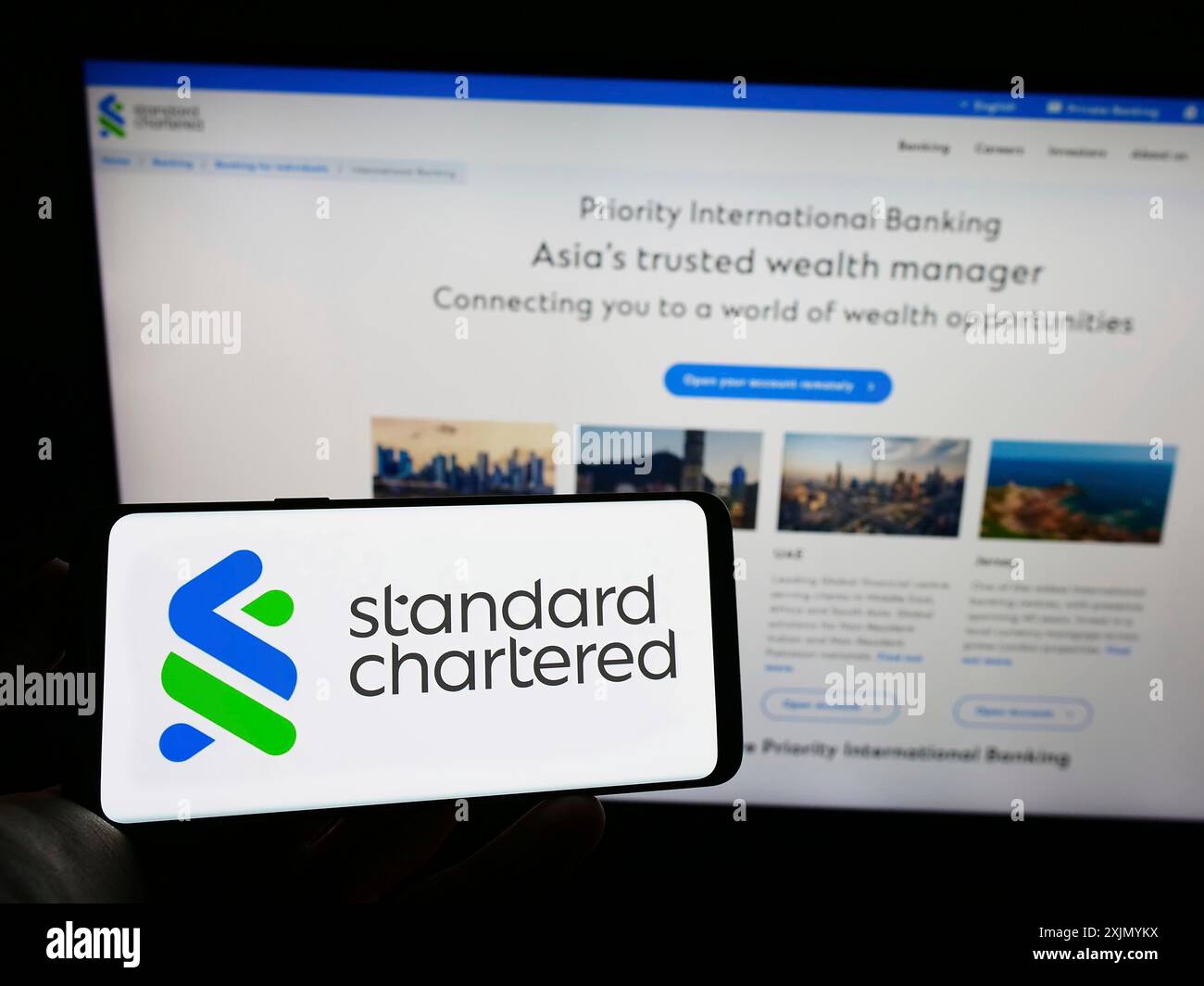 Stuttgart, Allemagne, 01-07-2023 : personne tenant un téléphone portable avec le logo de la société financière Standard Chartered plc sur l'écran devant l'entreprise Banque D'Images