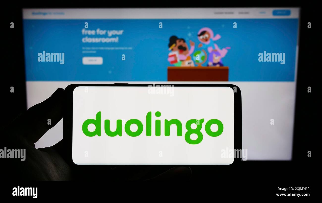 Stuttgart, Allemagne, 01-07-2023 : personne tenant un smartphone avec le logo de la société de technologie éducative Duolingo Inc. sur l'écran devant le site Web. Banque D'Images