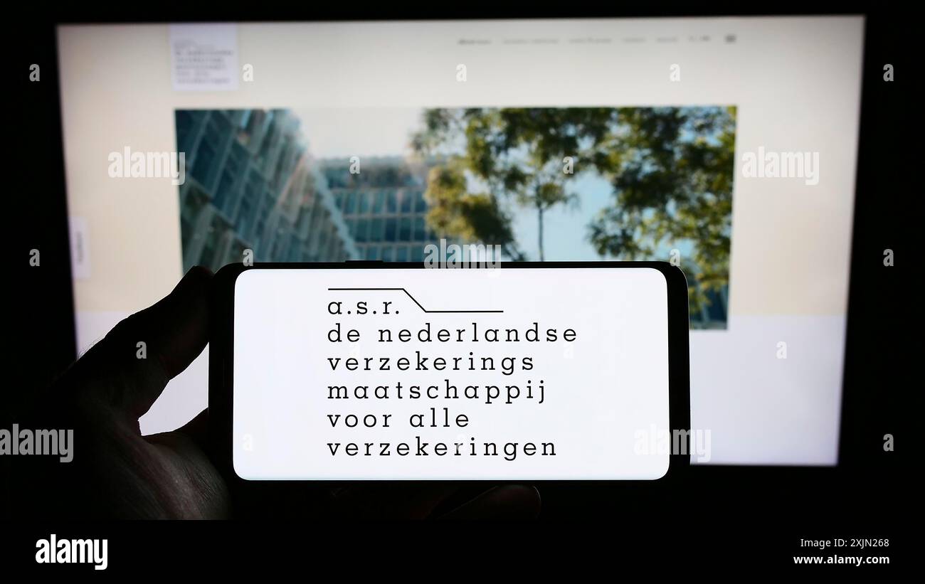 Stuttgart, Allemagne, 01-29-2023, personne tenant un smartphone avec le logo de la compagnie d'assurance néerlandaise ASR Nederland N.V. sur l'écran devant le site. Banque D'Images
